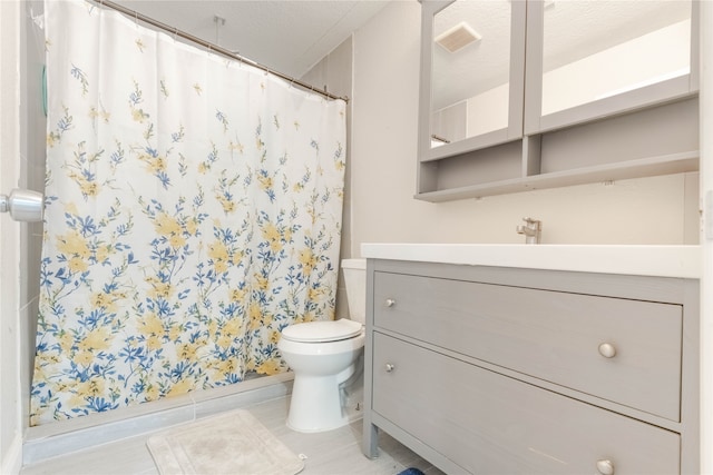 bathroom with curtained shower, tile patterned flooring, toilet, vanity, and a textured ceiling