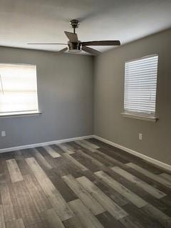 empty room with dark wood-type flooring and ceiling fan