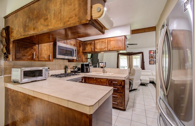 kitchen featuring kitchen peninsula, tile counters, sink, and appliances with stainless steel finishes