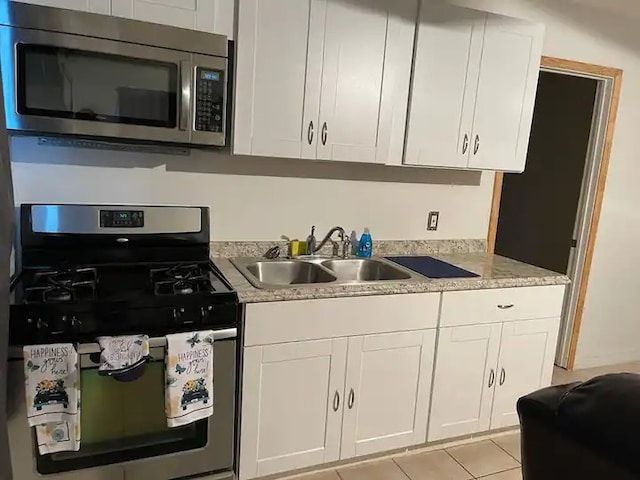 kitchen with white cabinetry, appliances with stainless steel finishes, sink, and light tile patterned floors