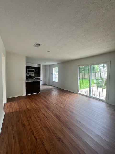 unfurnished living room with a textured ceiling and dark hardwood / wood-style floors