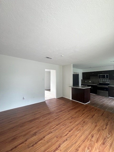 unfurnished living room with dark wood-type flooring and a textured ceiling