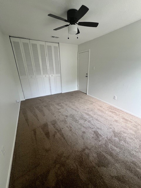 unfurnished bedroom with a closet, a textured ceiling, ceiling fan, and carpet floors