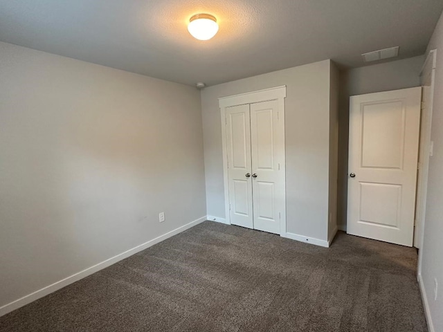 unfurnished bedroom featuring a closet and dark colored carpet