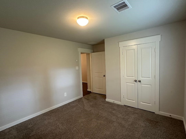 unfurnished bedroom with dark colored carpet and a closet