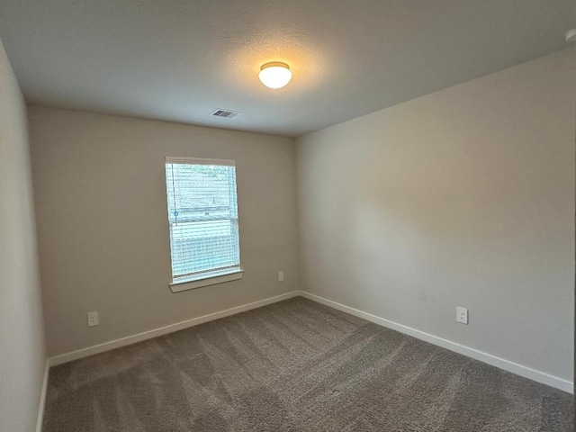 unfurnished room with a textured ceiling and dark colored carpet