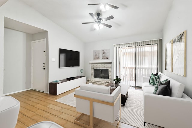 living room with ceiling fan, a fireplace, vaulted ceiling, and light wood-type flooring