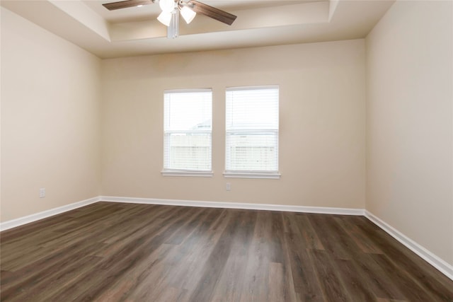 unfurnished room featuring a tray ceiling, dark wood-type flooring, and ceiling fan