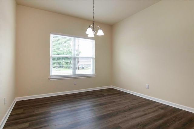 spare room with dark wood-type flooring and a notable chandelier