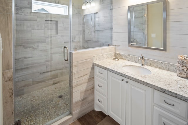 bathroom featuring hardwood / wood-style flooring, vanity, and a shower with shower door