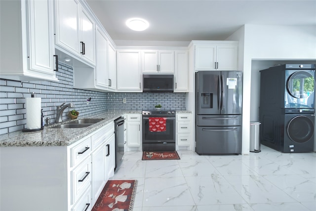 kitchen featuring stainless steel appliances, sink, stacked washer and dryer, and white cabinetry