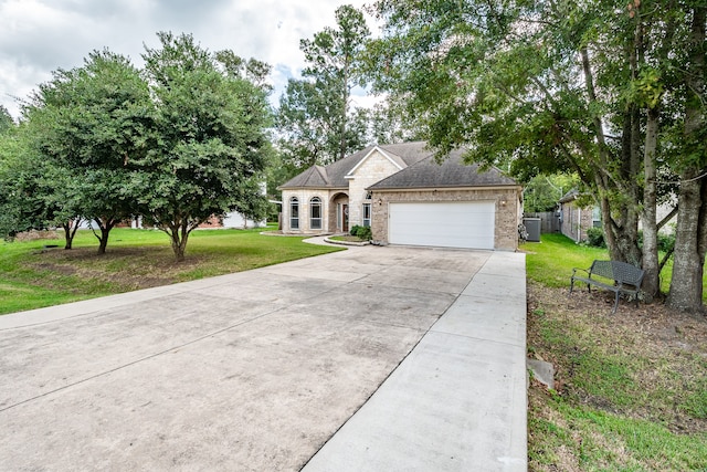 single story home with cooling unit, a garage, and a front yard