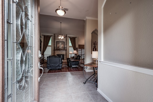 foyer entrance with hardwood / wood-style flooring, a stone fireplace, and crown molding