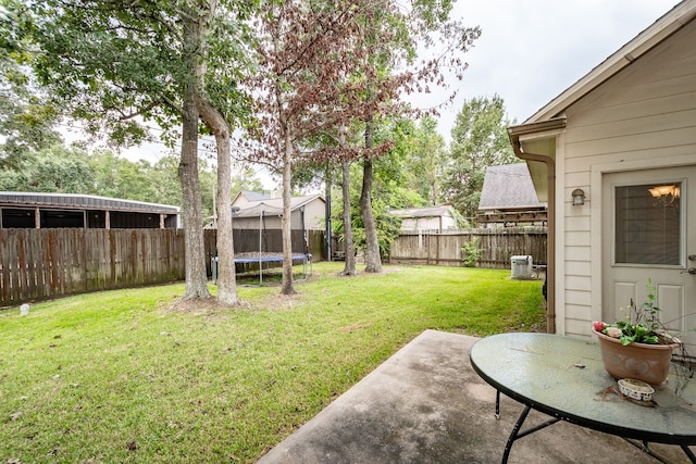 view of yard with a trampoline and a patio