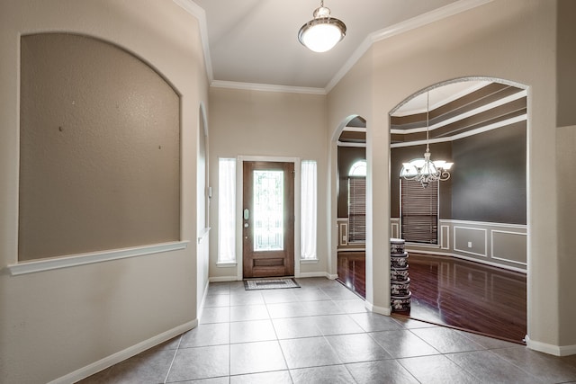 entryway featuring light tile patterned floors, crown molding, and a chandelier