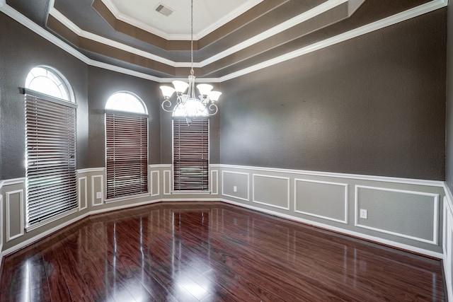 unfurnished room featuring a chandelier, hardwood / wood-style floors, a raised ceiling, and ornamental molding