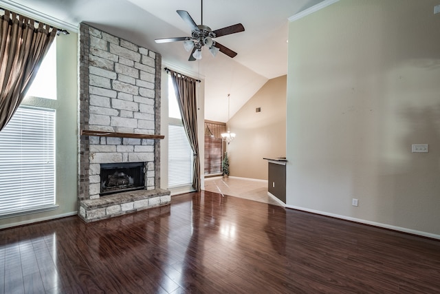 unfurnished living room with ceiling fan with notable chandelier, a healthy amount of sunlight, wood-type flooring, and a fireplace