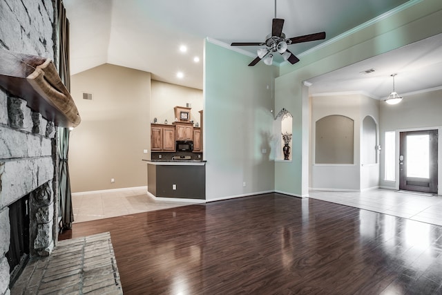 unfurnished living room featuring vaulted ceiling, ceiling fan, light wood-type flooring, a fireplace, and ornamental molding