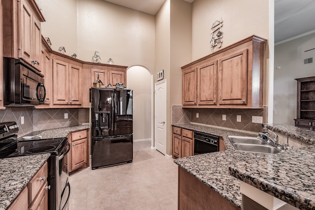 kitchen with backsplash, sink, black appliances, and a high ceiling