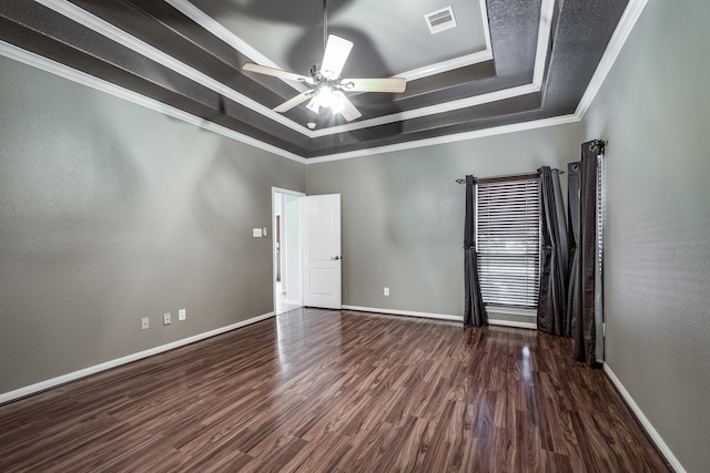 empty room featuring dark hardwood / wood-style floors, ceiling fan, a raised ceiling, and ornamental molding