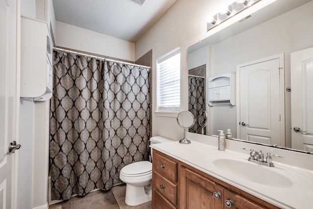 bathroom with toilet, vanity, and tile patterned floors