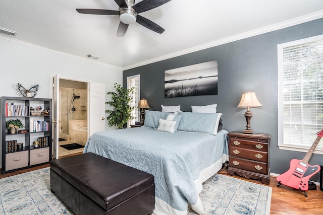 bedroom with connected bathroom, crown molding, hardwood / wood-style flooring, ceiling fan, and multiple windows