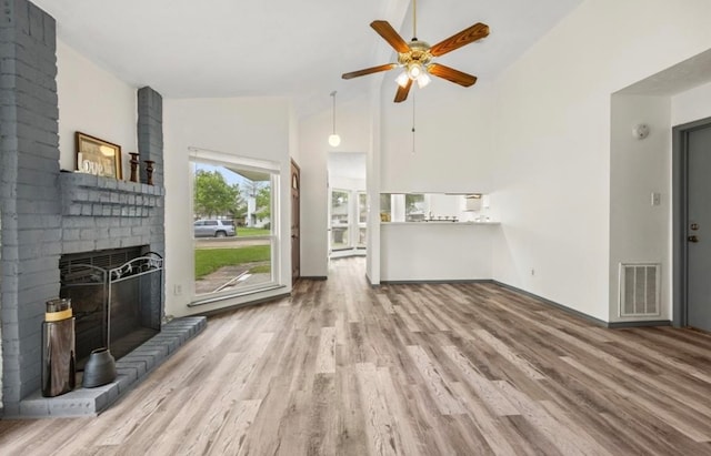 unfurnished living room featuring high vaulted ceiling, light hardwood / wood-style floors, ceiling fan, and a fireplace