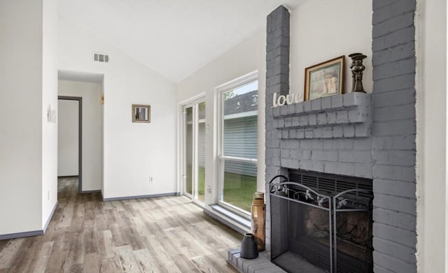 interior space featuring lofted ceiling, light hardwood / wood-style flooring, and a brick fireplace