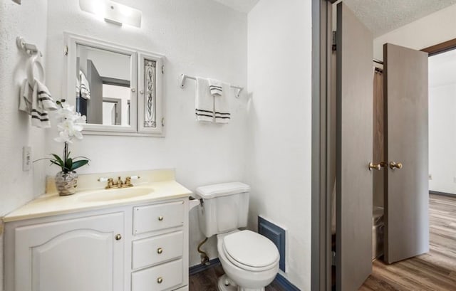 bathroom with a textured ceiling, vanity, toilet, and hardwood / wood-style flooring