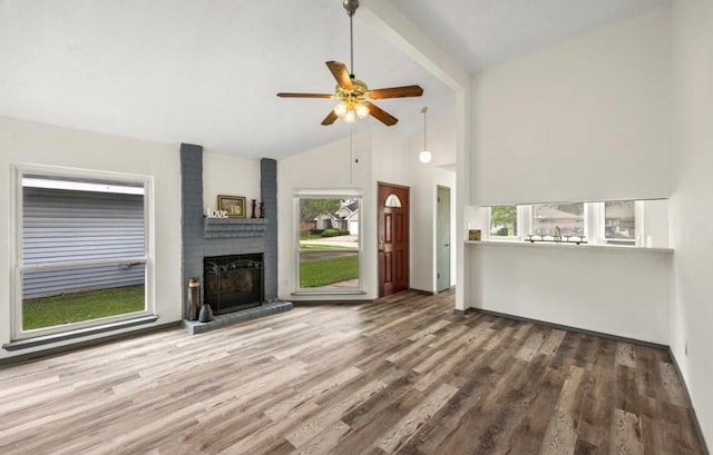 unfurnished living room with hardwood / wood-style flooring, a healthy amount of sunlight, ceiling fan, and a brick fireplace