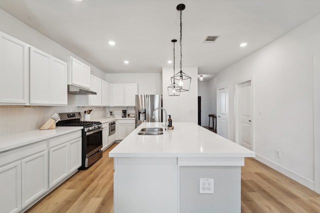 kitchen featuring white cabinetry, stainless steel appliances, a center island with sink, and sink