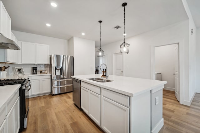 kitchen with light hardwood / wood-style flooring, sink, a kitchen island with sink, white cabinetry, and appliances with stainless steel finishes