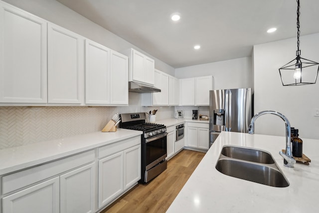 kitchen with white cabinetry, sink, appliances with stainless steel finishes, pendant lighting, and light wood-type flooring