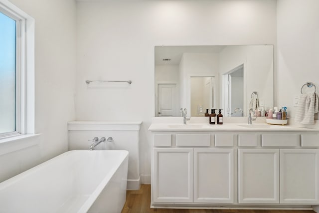 bathroom with hardwood / wood-style floors, vanity, and a tub