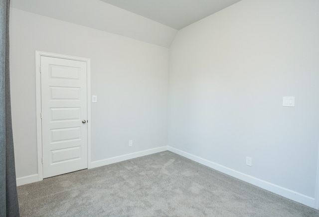 empty room with light colored carpet and vaulted ceiling