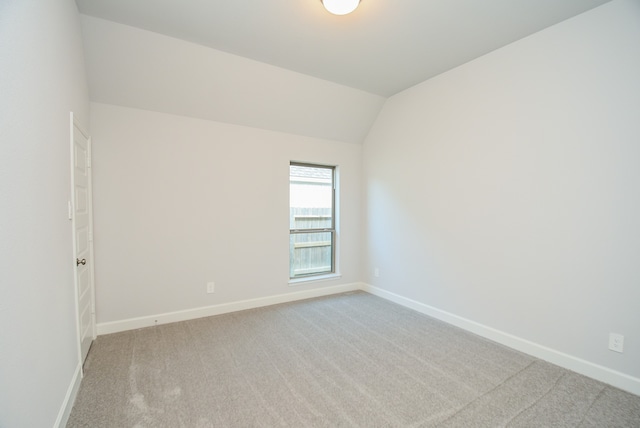 carpeted empty room featuring lofted ceiling