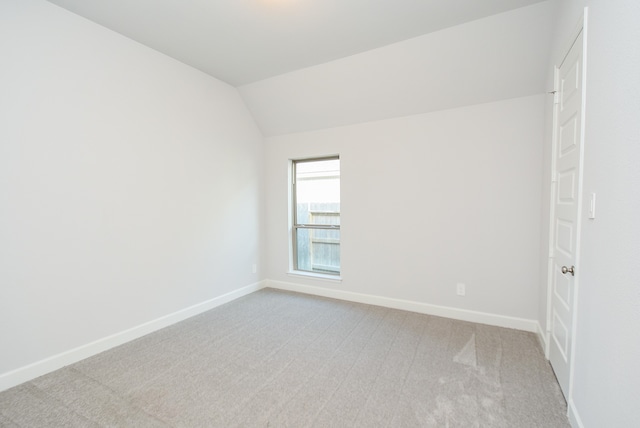 spare room featuring light carpet and lofted ceiling