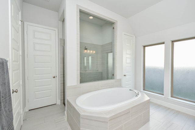 bathroom with lofted ceiling, separate shower and tub, and tile patterned flooring