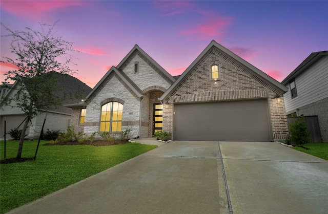 french country inspired facade featuring a lawn and a garage