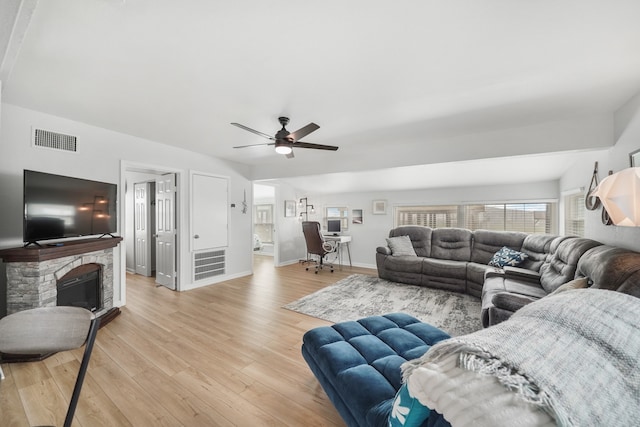 living room featuring ceiling fan, a fireplace, and light hardwood / wood-style floors