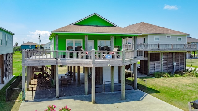 rear view of house with a yard, a wooden deck, and a patio