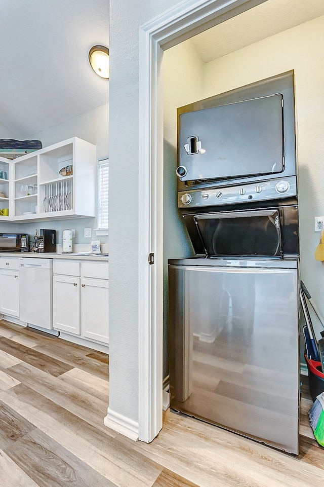 laundry area with stacked washing maching and dryer and light hardwood / wood-style flooring