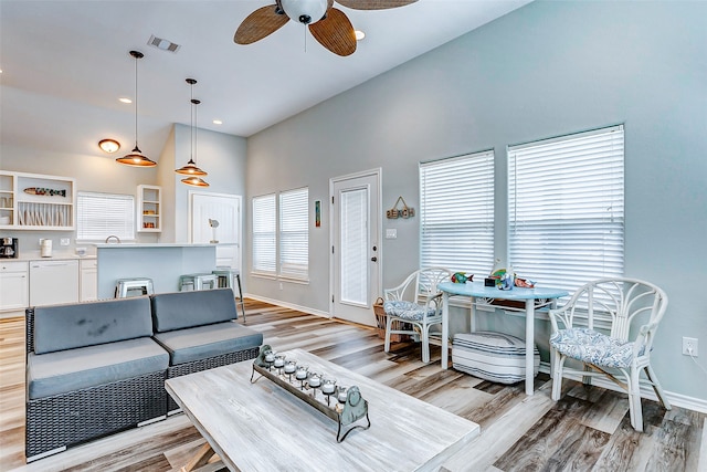 living room featuring a towering ceiling, light hardwood / wood-style flooring, and ceiling fan