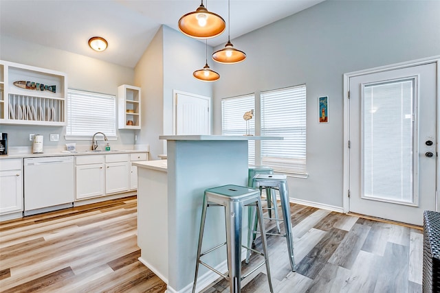 kitchen with white cabinets, dishwasher, a healthy amount of sunlight, pendant lighting, and a kitchen bar