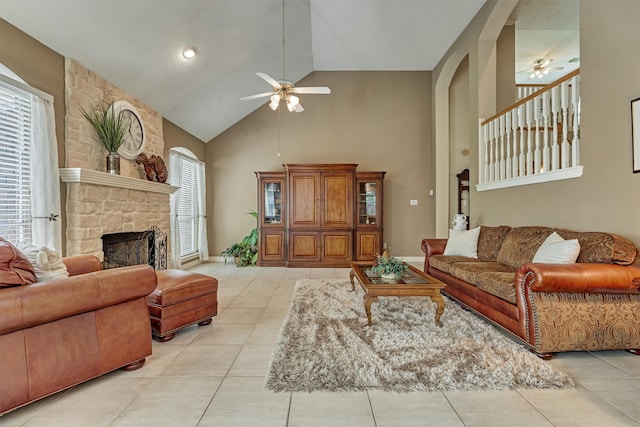 living room featuring light tile patterned floors, high vaulted ceiling, a wealth of natural light, and a stone fireplace