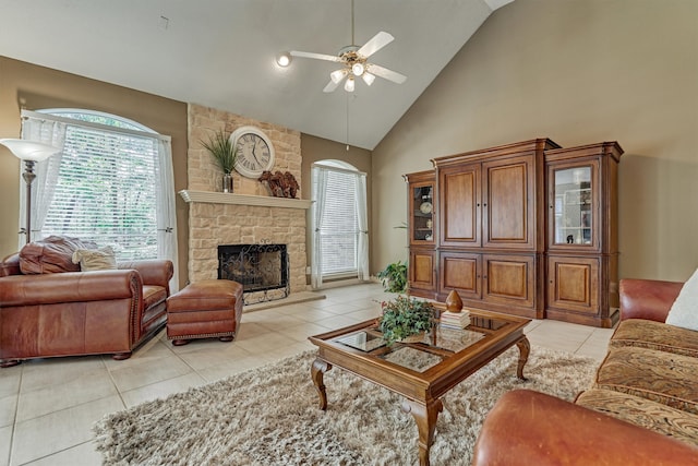 living room with light tile patterned floors, ceiling fan, a stone fireplace, and high vaulted ceiling