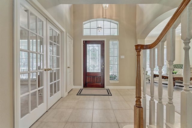 entrance foyer featuring stairs, french doors, baseboards, and light tile patterned floors