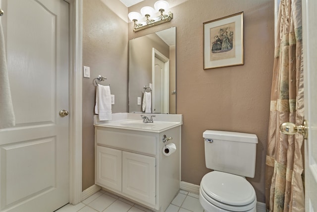 bathroom with tile patterned flooring, baseboards, vanity, and toilet