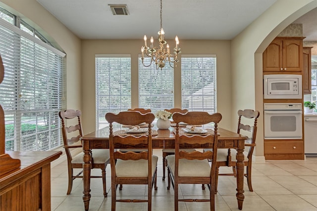 dining room featuring arched walkways, light tile patterned floors, visible vents, and a notable chandelier