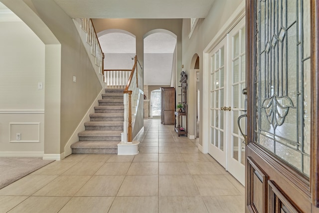 entryway with stairs, light tile patterned flooring, and baseboards